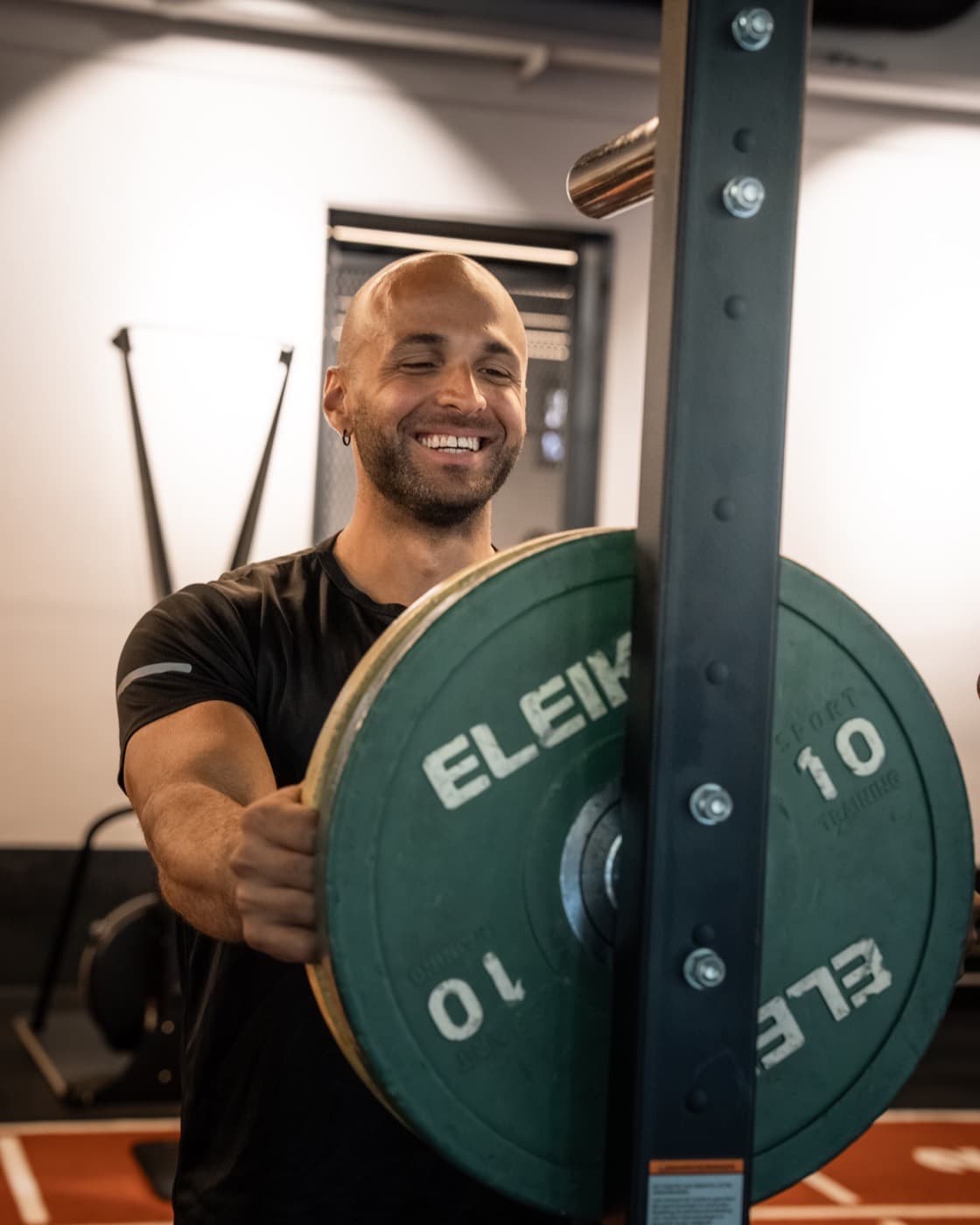 Claudio loading a plate onto the bar in the gym